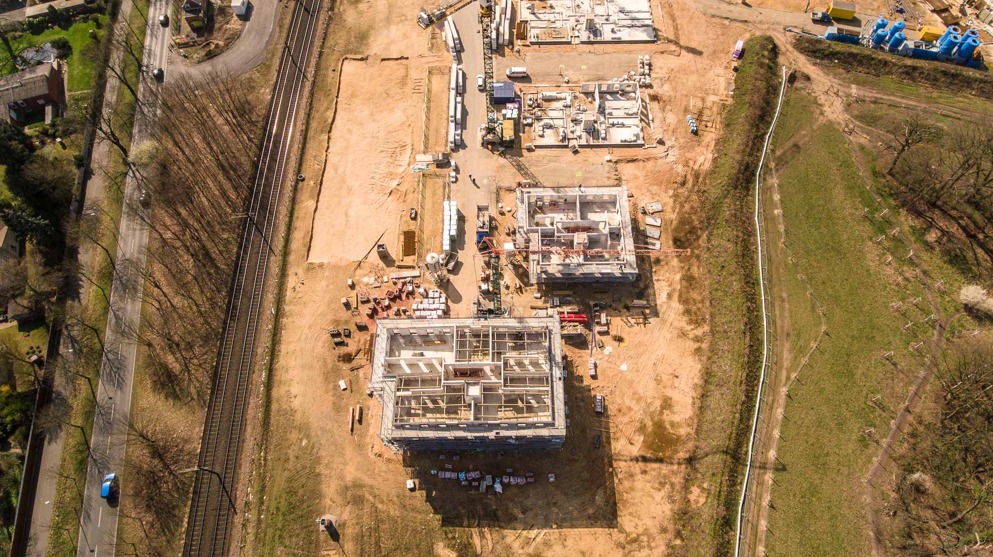 Luftaufnahme senkrecht von oben: Rohbauten neben der Bahntrasse