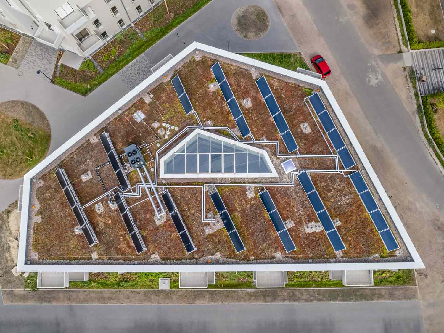 Luftaufnahme senkrecht von oben: begrüntes Dach mit Solarmodulen und Oberlicht