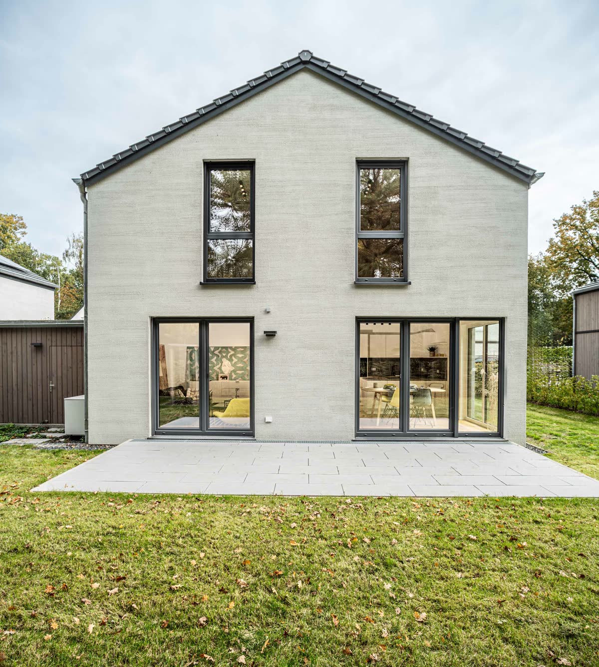 Gartenseite des Musterhauses mit Terrasse und großen Fensterflächen